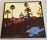Front cover of the Eagles' Hotel California vinyl album featuring a building exterior and tall palm trees at sunset.