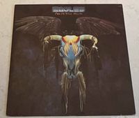 Front cover of the vinyl album showing a stylized bull skull with wings with dark colors on a brownish black background. Album title and band name at the top.