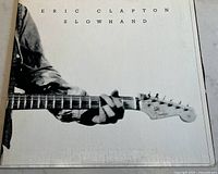 Close-up of album cover showing black-and-white photo of Eric Clapton playing guitar with title Slowhand.