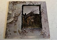 Front cover of Led Zeppelin IV vinyl album showing man carrying sticks with worn and peeling edges.
