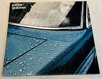 Front cover of Peter Gabriel 'Car' vinyl album showing blue car detail with water droplets and person inside car visible.
