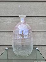 Front view of a glass flower vase showing pinkish stripes and crackled clear texture at base