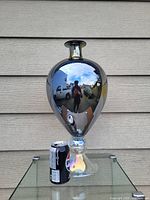 Front view showing the reflective dark metallic finish of the large glass vase with clear reflections and a soda can for scale indicating 15 inch height.