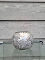 Art glass vase with etched floral design on a wooden background.