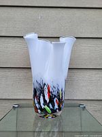 Front view of tall white glass vase with multi-colored confetti design at base and fluted petal top edge.