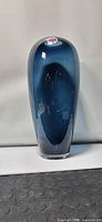 Front view of large blue glass vase showing tall, slender body and smooth polished finish.