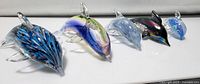 All 5 glass dolphin figurines placed in a row showing variety of colors and designs.