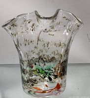 Front and side views of a small glass candle holder with wavy rim and multicolored accents