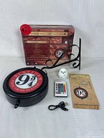 Photo showing all items in the set: boxed lamp, metal bracket, round illuminated sign, remote, USB cable, instruction manual, and snowy owl figurine.