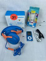 Full set of kids audio bundle showing headphones, boxed MP3 player, earbuds, and USB cable