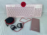 Overview of pink wireless keyboard, Toplay sports headphones with red cable and carrying case, and pink Poweradd power bank on flat surface.