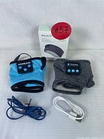 Full view of both Perytong sleep headphone mask in dark gray and Kidsband blue Bluetooth headband with their USB charging cables and Perytong box.