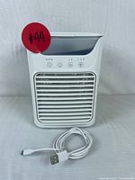 Front view of Airlysita portable air conditioner showing vent grille, control buttons and USB cable coiled in front.