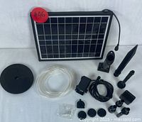 Complete solar powered water fountain pump kit components arranged on white background showing panel, pump, tubing, nozzles, and stakes.