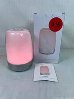 Sunrise alarm clock illuminated pink next to original box and user manual.