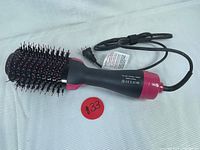 Full view of the black and pink one-step hair dryer and volumizer hot air brush showing the bristle head and power cord.