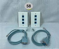 Two Extradigital RJ45 to DB9 serial adapter cables and two white wall plates with three RJ45 jacks each, arranged side by side on a light surface.