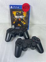 Photo of Call of Duty: Black Ops 4 PS4 game case upright with two black DualShock 4 wireless controllers in front of it.