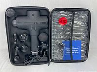 Percussion massager gun with multiple interchangeable massage heads, charging cable, user manual, and carrying case shown