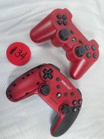 Photo showing both controllers: one original Sony red DualShock 3 controller and one EUORETO red wireless controller with black grips.
