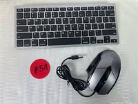 Photo showing OMOTON keyboard with black keys and silver frame next to wired USB computer mouse with cord coiled beside it.