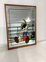 Full view of rectangular mirror with wooden frame featuring printed Pinocchio image.