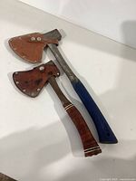 Photo showing two Eastwing hatchets side by side with leather sheaths, displaying overall size and condition.