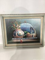Full view of the framed Indigenous American still life painting with pottery and flowers