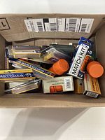 Photo of the box containing various match packs and orange waterproof containers, showing mixed assortment of matches and containers.