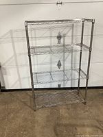 Full front view of metal wire shelving unit showing four shelves and its overall shape and size.