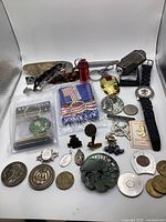 Full lot showing coins, watches, keychains, pins and memorabilia including Iron Man mask and U.S. Army keychain.