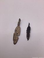 Two sterling silver feather pendants shown on white background.