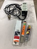 Full view of the welding rods and electrode holder with power cord on a white surface.