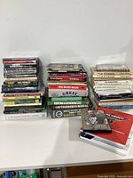 Photo showing the full collection of survival-related books, DVDs, and manuals stacked on a white surface.