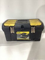 Closed Stanley 18-inch black toolbox with yellow latches and handle, showing exterior label.