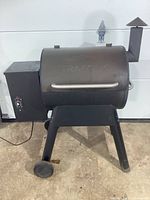 Front view of barrel smoker grill with hopper, wheels, legs and handle