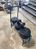 Weight plates stacked on blue bench, including barbell and dumbbells