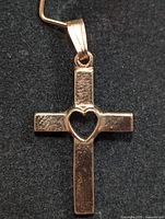 Close-up front view of the 10KT gold cross pendant showing heart cutout detail and textured finish.