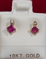 Front view of ruby and diamond 10KT gold stud earrings in white display card.