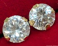 Close-up of the cubic zirconia stones in 14KT gold prong settings of the earrings on red fabric background