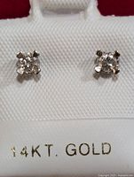 Front view of the diamond stud earrings set in 14K gold on white textured holder