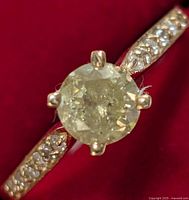 Top view showing center diamond and shoulder pavé stones on red background