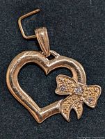 Pendant front view on black background showing open heart shape and bow with white stones