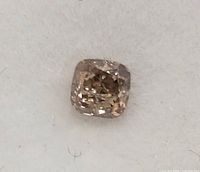 Close-up front view of the single cushion cut champagne diamond on a white background showing facets and color tone.