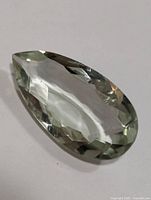 Close-up photo of faceted pear-shaped green amethyst showing clarity and faceting details.