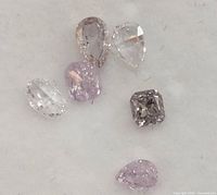Close-up front view of six assorted pink and white diamonds on white background.