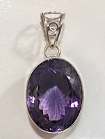Front view of the oval faceted deep purple amethyst pendant set in silver, showing color and cut of the gemstone.