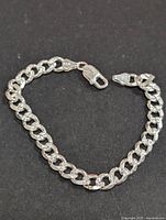 Full view of the silver chain link bracelet showing the clasp and length.