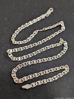 Full view of the silver chain laid out on a dark surface showing entire length and chain style.