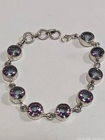 Silver bracelet with round mystic topaz gemstones set in silver bezels, displayed on neutral background.